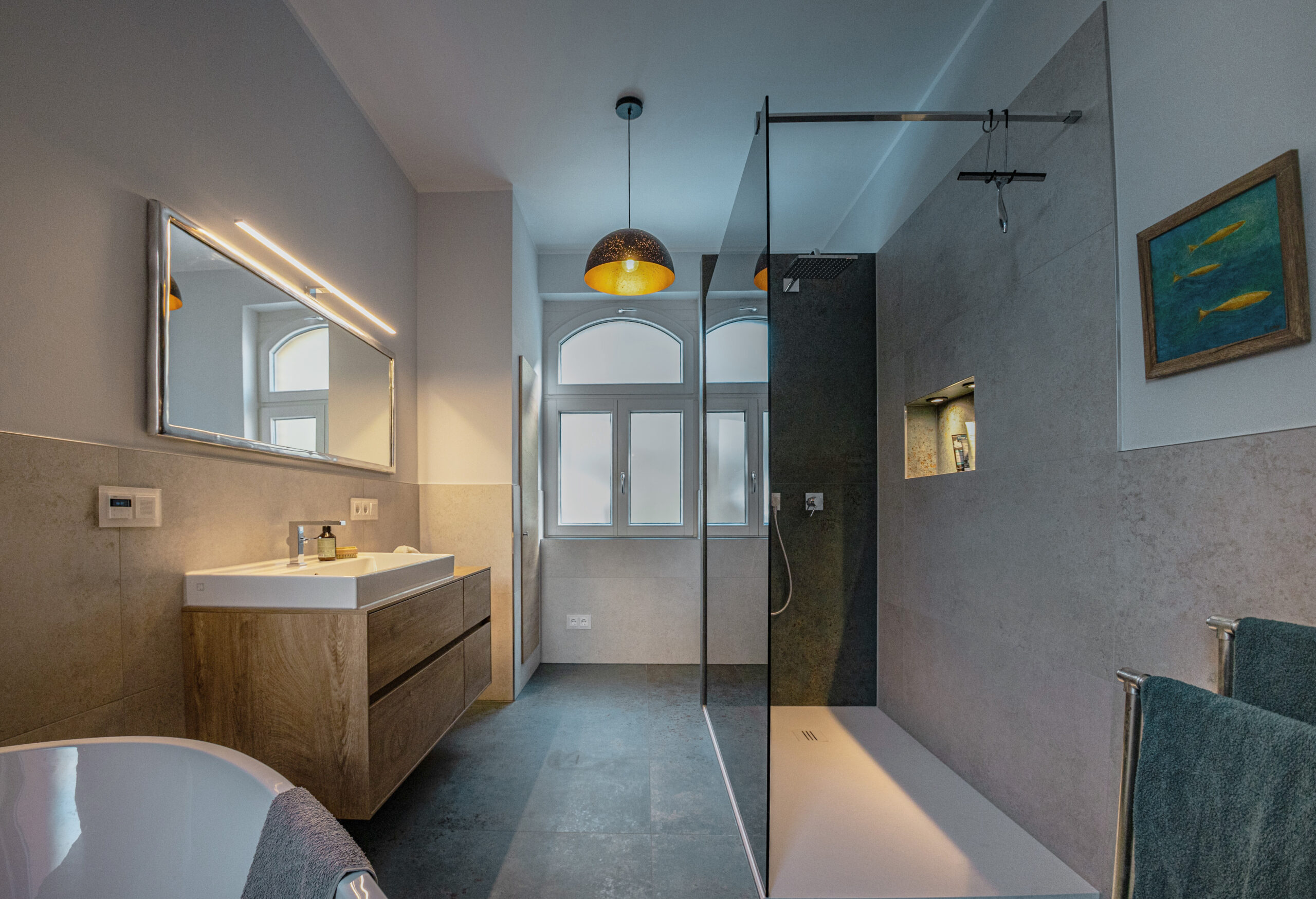 Vollständig saniertes Badezimmer von Lehof mit bodengleicher Walk-in-Dusche, Glasabtrennung, einem modernen Holz-Waschtisch und dunklen Bodenfliesen. Titel: Komplett-Badsanierung-Lehof-Walk-In-Dusche